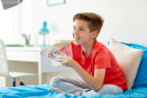 Image of happy boy with gamepad playing video game at home
