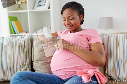 Image of happy pregnant woman with smartphone at home