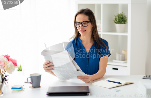 Image of businesswoman reading newspaper at office