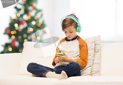 Image of boy with smartphone and headphones at christmas