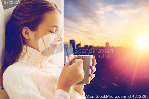 Image of girl with tea mug sitting at home window