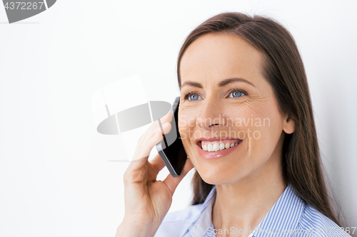 Image of businesswoman calling on smartphone at office