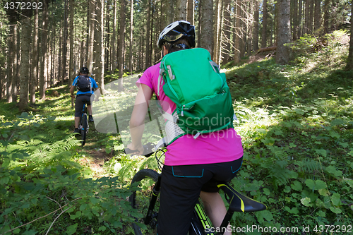 Image of Active sporty couple riding mountain bikes on forest trail .