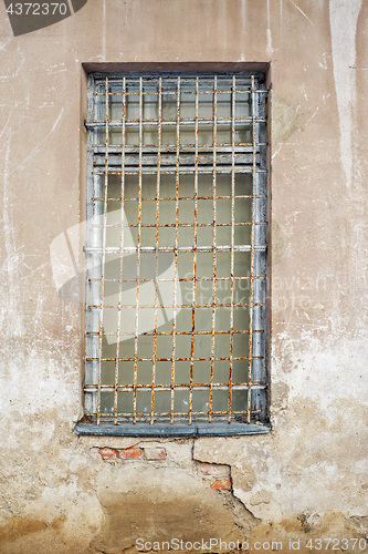 Image of abandoned cracked stucco wall with window grilles