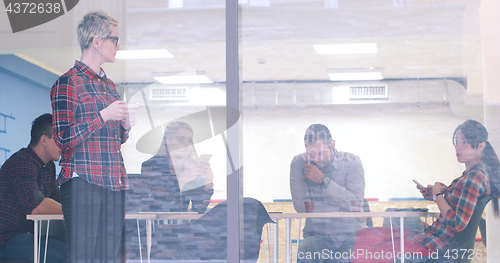 Image of Business Woman Looking Through A Window And using On A Cell Phon