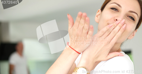 Image of woman sending kiss to camera in modern apartment