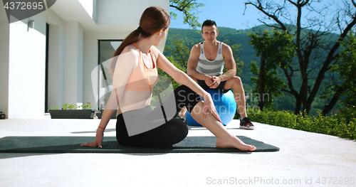 Image of Couple Doing Stretching Exercises Together in front of luxury vi