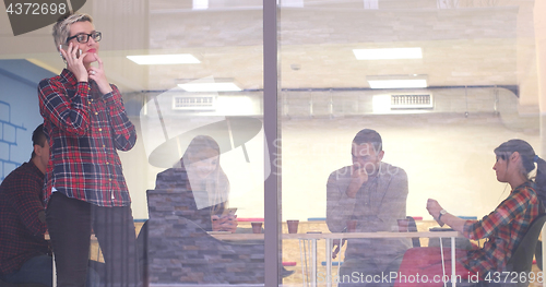 Image of Business Woman Looking Through A Window And using On A Cell Phon