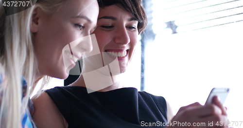 Image of two attractive business women with a cell phone discuss business