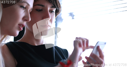 Image of two attractive business women with a cell phone discuss business