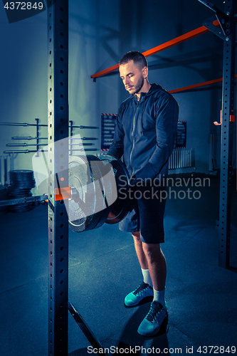 Image of Portrait of super fit muscular young man working out in gym with barbell