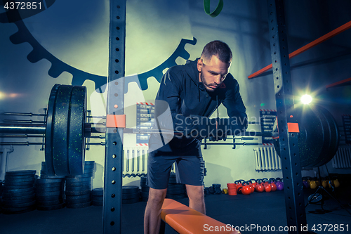 Image of Portrait of super fit muscular young man working out in gym with barbell