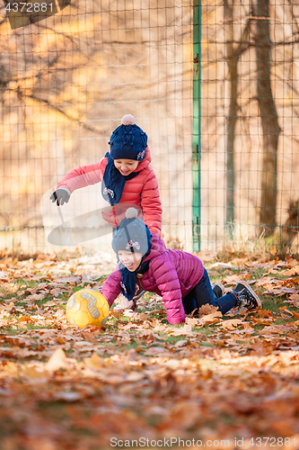 Image of The two little baby girls playing in autumn leaves