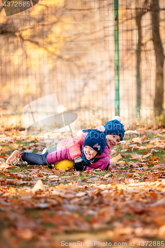 Image of The two little baby girls playing in autumn leaves