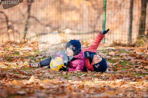 Image of The two little baby girls playing in autumn leaves