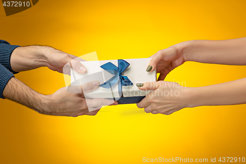 Image of The closeup picture of man and woman\'s hands with gift box