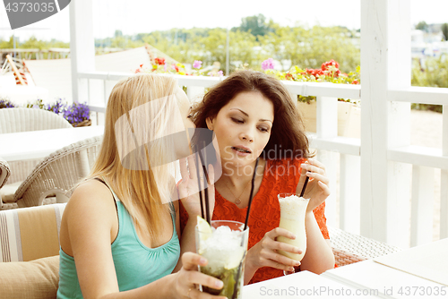 Image of portrait of two pretty modern girl friends in cafe open air inte