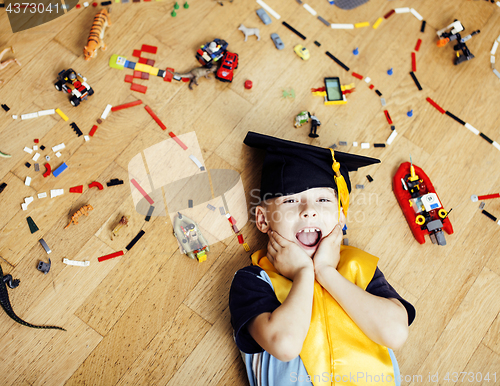 Image of little cute preschooler boy among toys at home in graduate