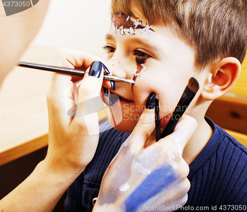 Image of little cute child making facepaint on birthday party, zombie Apocalypse facepainting, halloween preparing concept, lifestyle people 