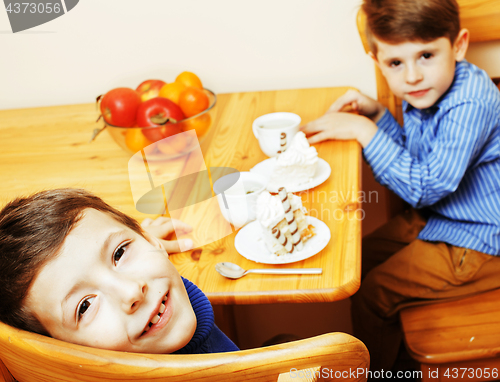 Image of little cute boys eating dessert on wooden kitchen. home interior