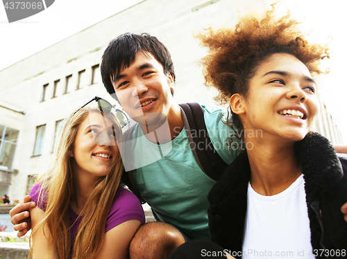 Image of cute group of teenages at the building of university with books huggings, back to school