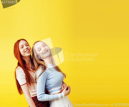 Image of lifestyle people concept: two pretty young school teenage girls having fun happy smiling on yellow background 