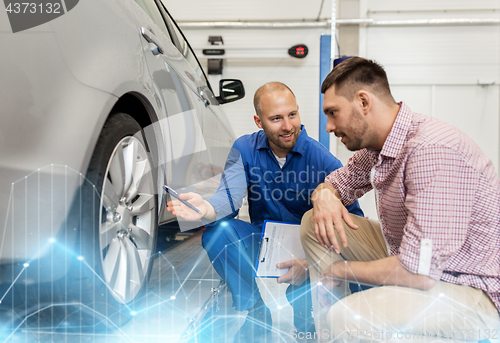 Image of auto mechanic with clipboard and man at car shop