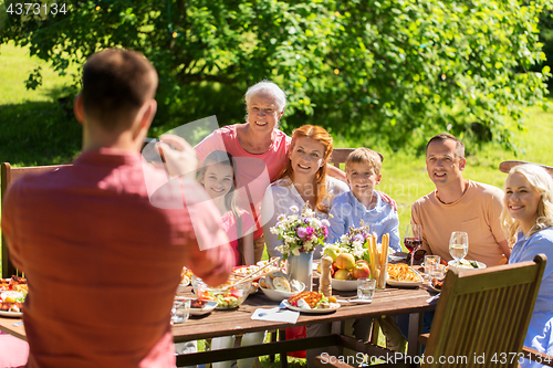 Image of happy family photographing by smartphone in summer