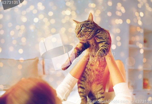 Image of young woman with cat lying in bed at home