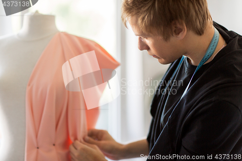 Image of fashion designer with dummy making dress at studio