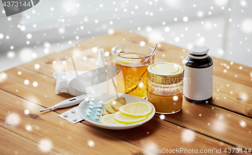 Image of drugs, thermometer, honey and cup of tea on wood