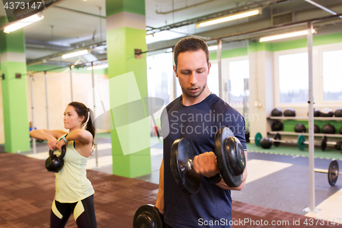 Image of man and woman with kettlebell exercising in gym