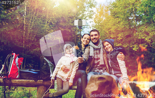 Image of family with smartphone taking selfie near campfire