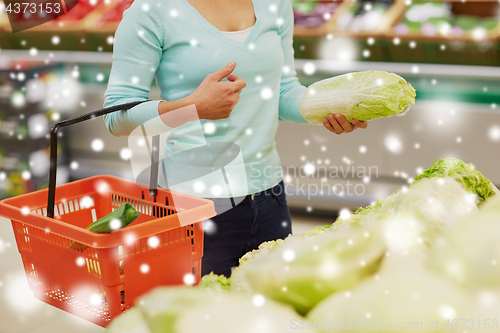 Image of woman with basket and chinese cabbage at grocery