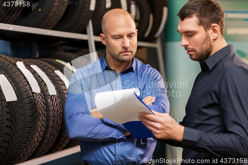 Image of customer and salesman at car service or auto store