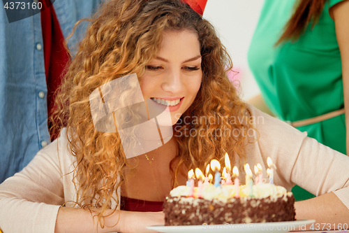 Image of happy woman with candles on birthday cake at party