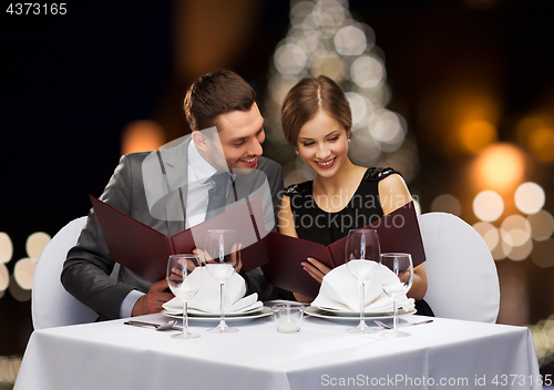 Image of smiling couple with menus at christmas restaurant