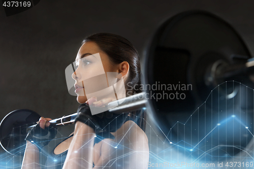 Image of young woman flexing muscles with barbell in gym