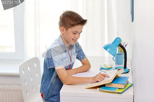 Image of student boy reading book at home table