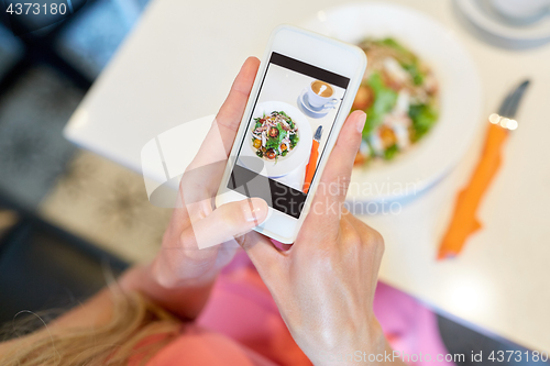 Image of woman with smartphone photographing food at cafe