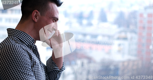 Image of Business Man Talking On Cell Phone, Looking Out Office Window