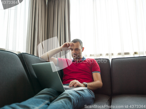 Image of Man using laptop in living room