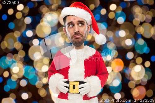 Image of sad man in santa costume over christmas lights