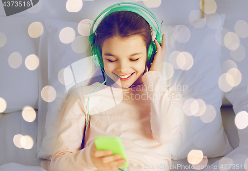 Image of girl with headphones listening to music in bed