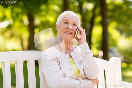 Image of happy senior woman calling on smartphone in summer