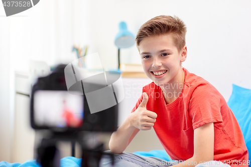 Image of happy boy with camera recording video at home