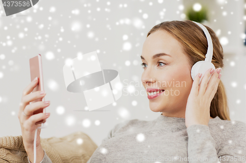 Image of woman with smartphone and headphones at home