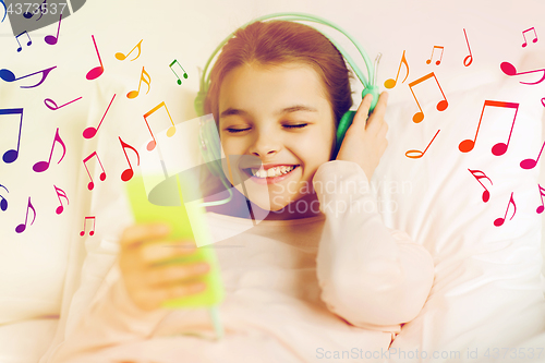Image of girl with headphones listening to music in bed