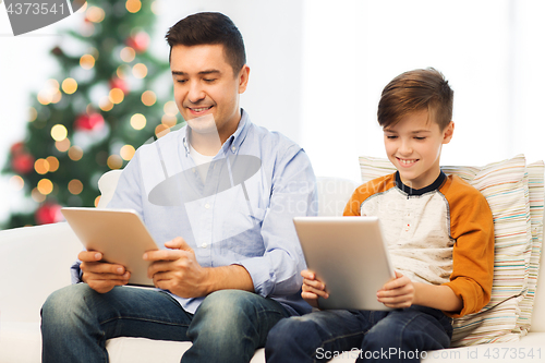 Image of happy father and son with tablet pc at christmas