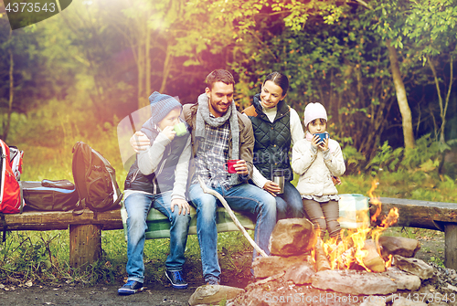 Image of happy family sitting on bench at camp fire